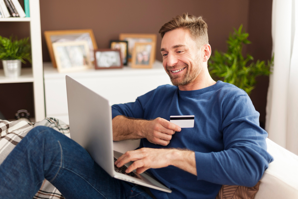 A man holding a credit card, paying off his car loan earlier through an online transaction.
