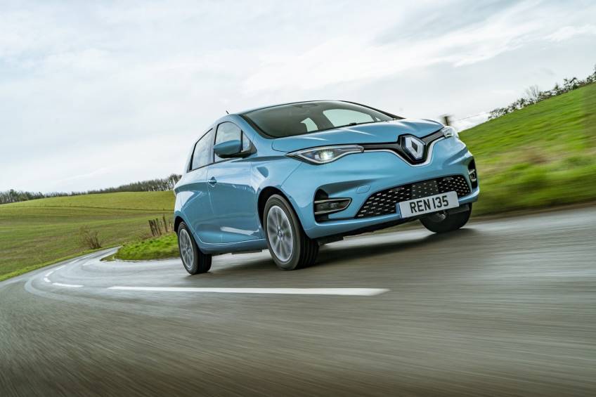 Powder blue 2 door Renault Zoe driving on the left hand side of country road in daytime